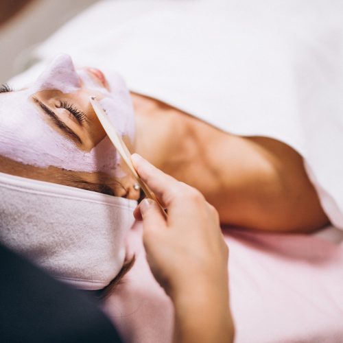 Cosmetologist applying mask on a face of client in a beauty salon