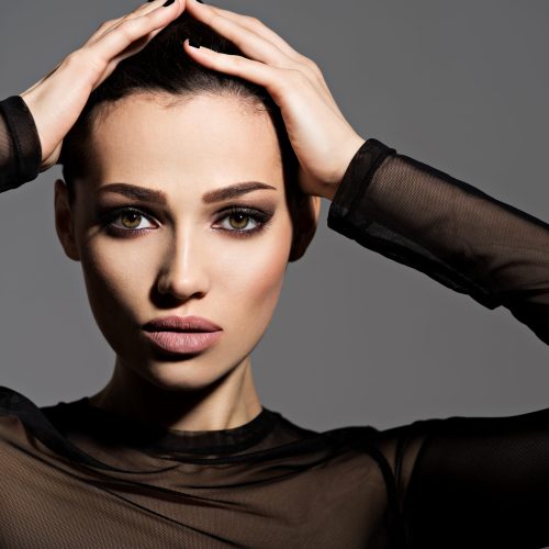 Face of a beautiful girl with smoky eyes makeup posing at studio over dark background