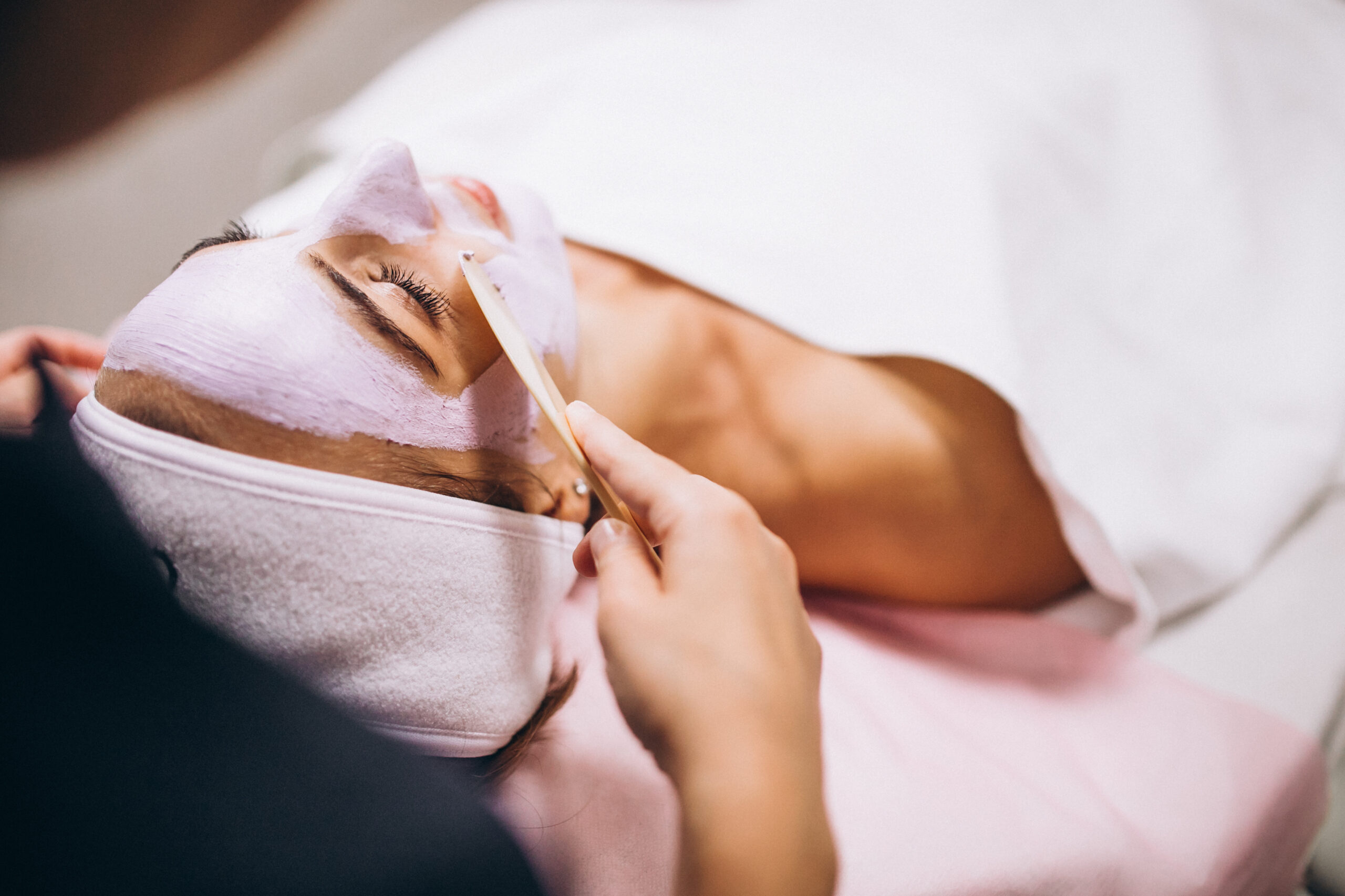 Cosmetologist applying mask on a face of client in a beauty salon
